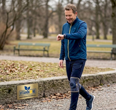 En man promenerar i parken med ett knästöd.