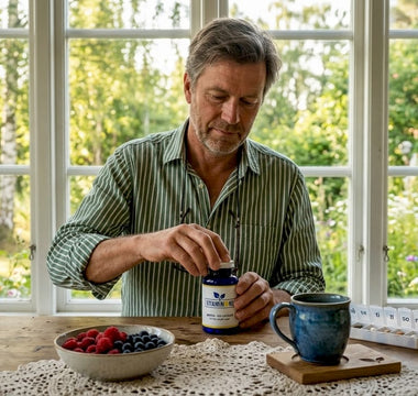En medelålders man sitter vid köksbordet och plockar med sina biotintabletter.